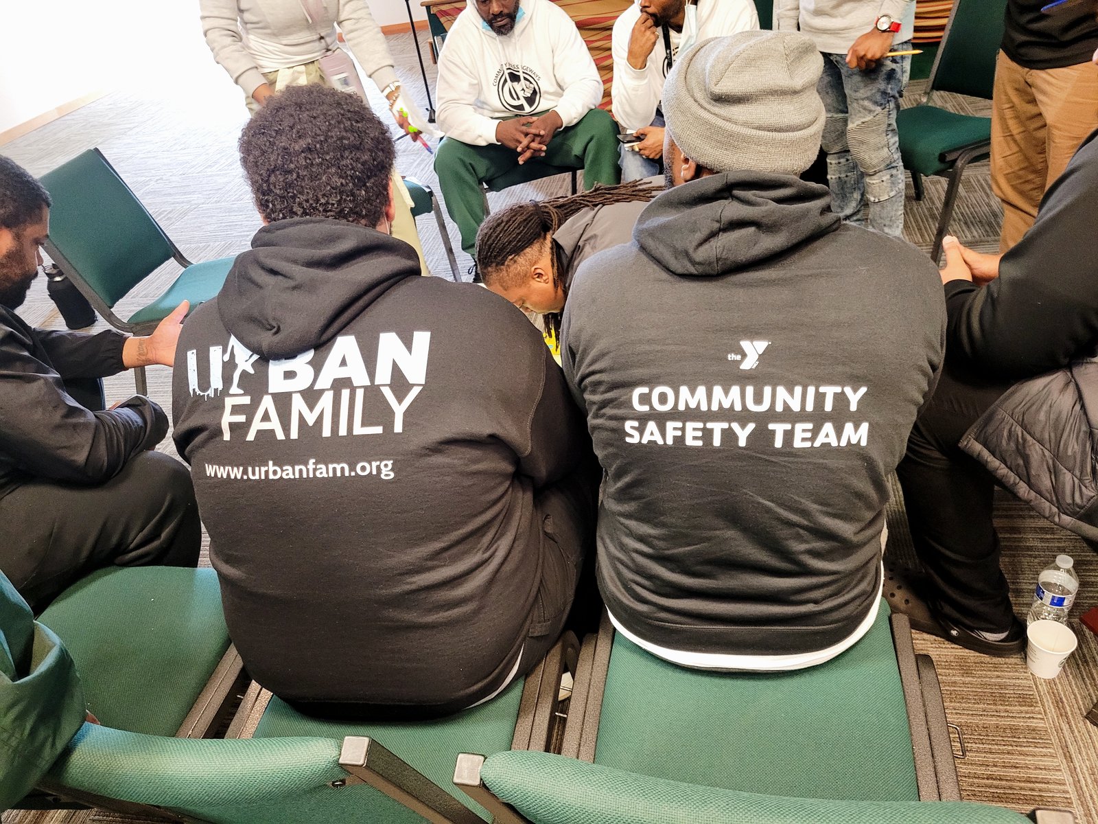 People seated in a meeting room wearing Urban Family and Community Safety Team sweatshirts