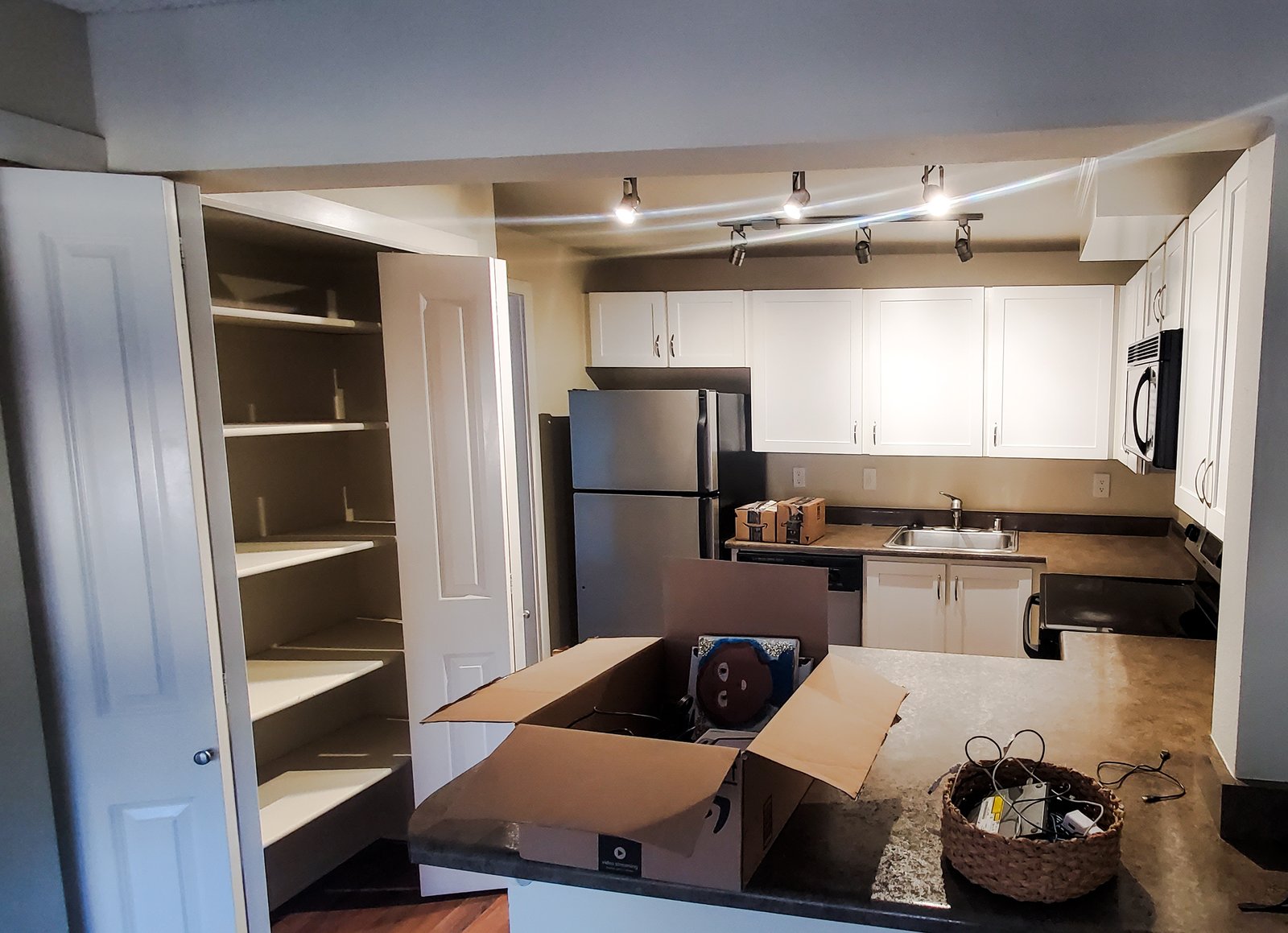 An empty apartment kitchen and living area with moving boxes on the floor