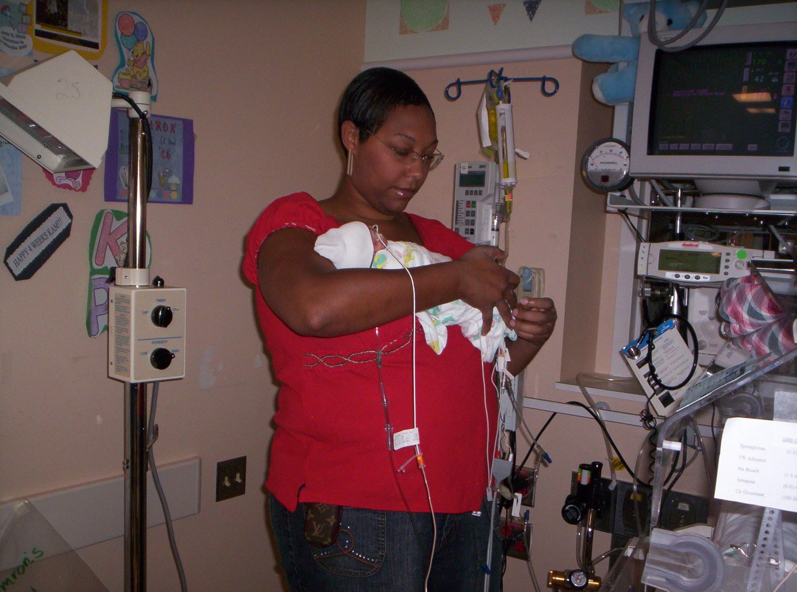 A mother holding her newborn in a hospital neonatal unit