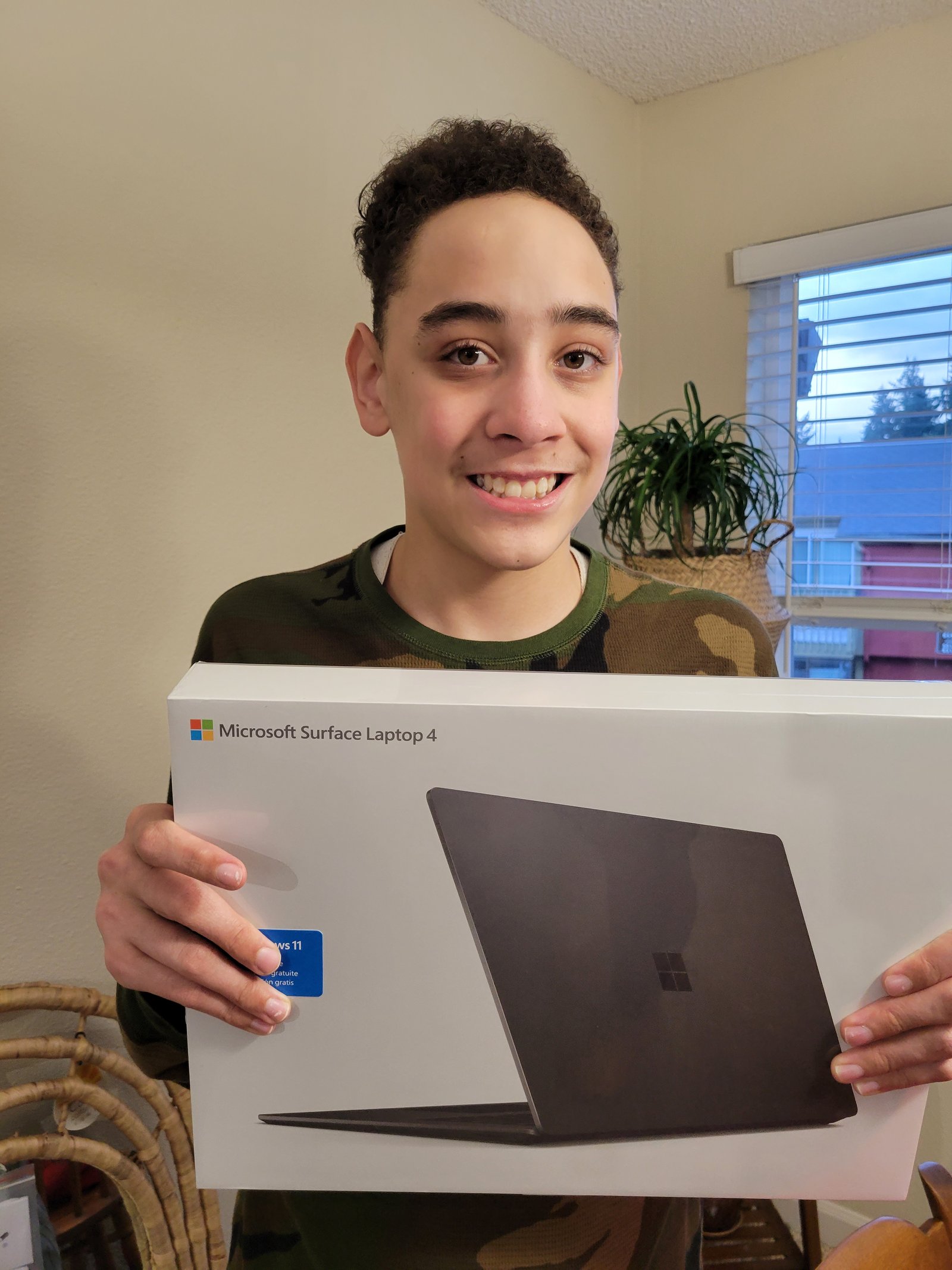 A teenager holding a boxed Microsoft Surface laptop