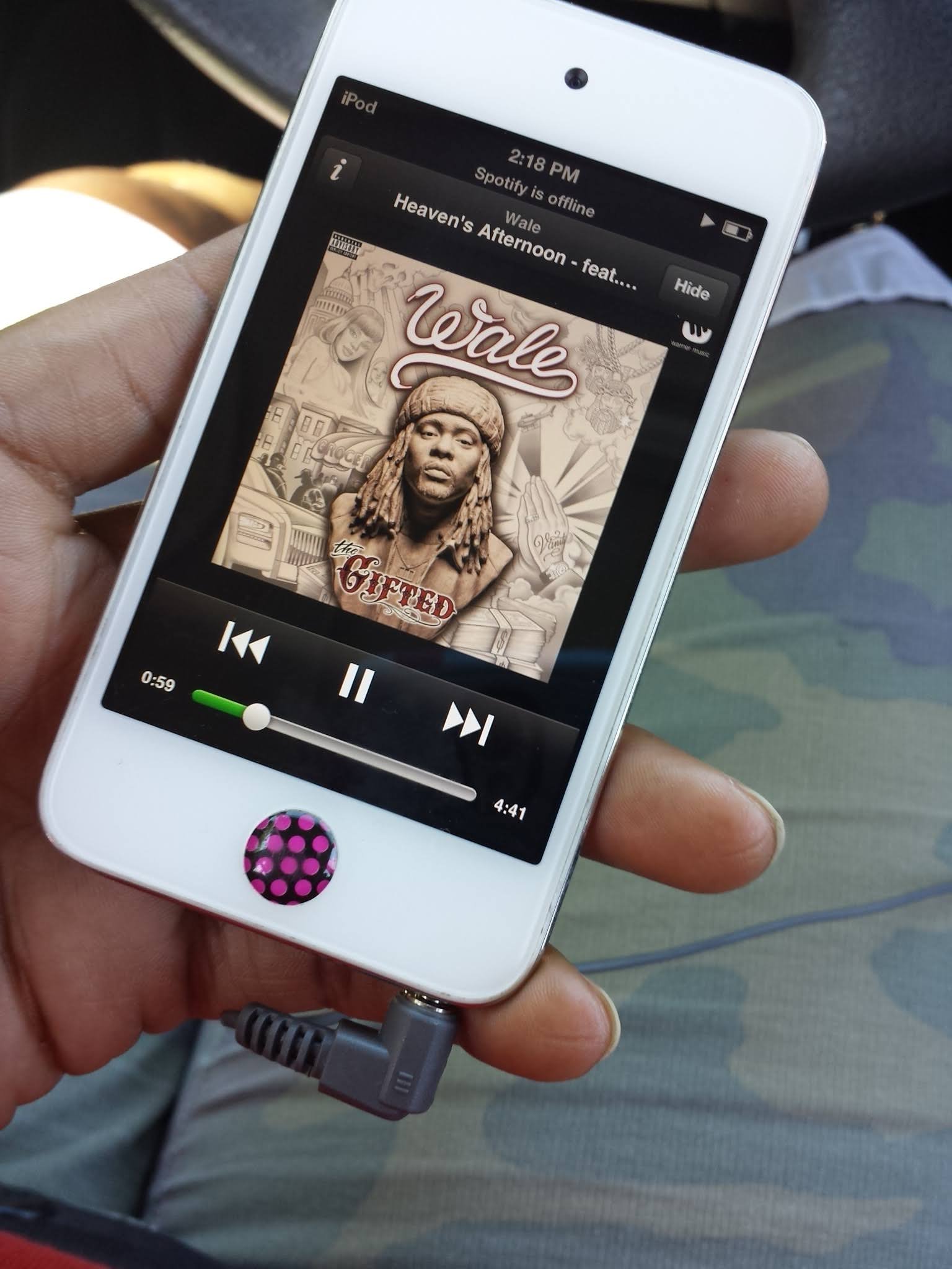 A hand holding an iPod playing music