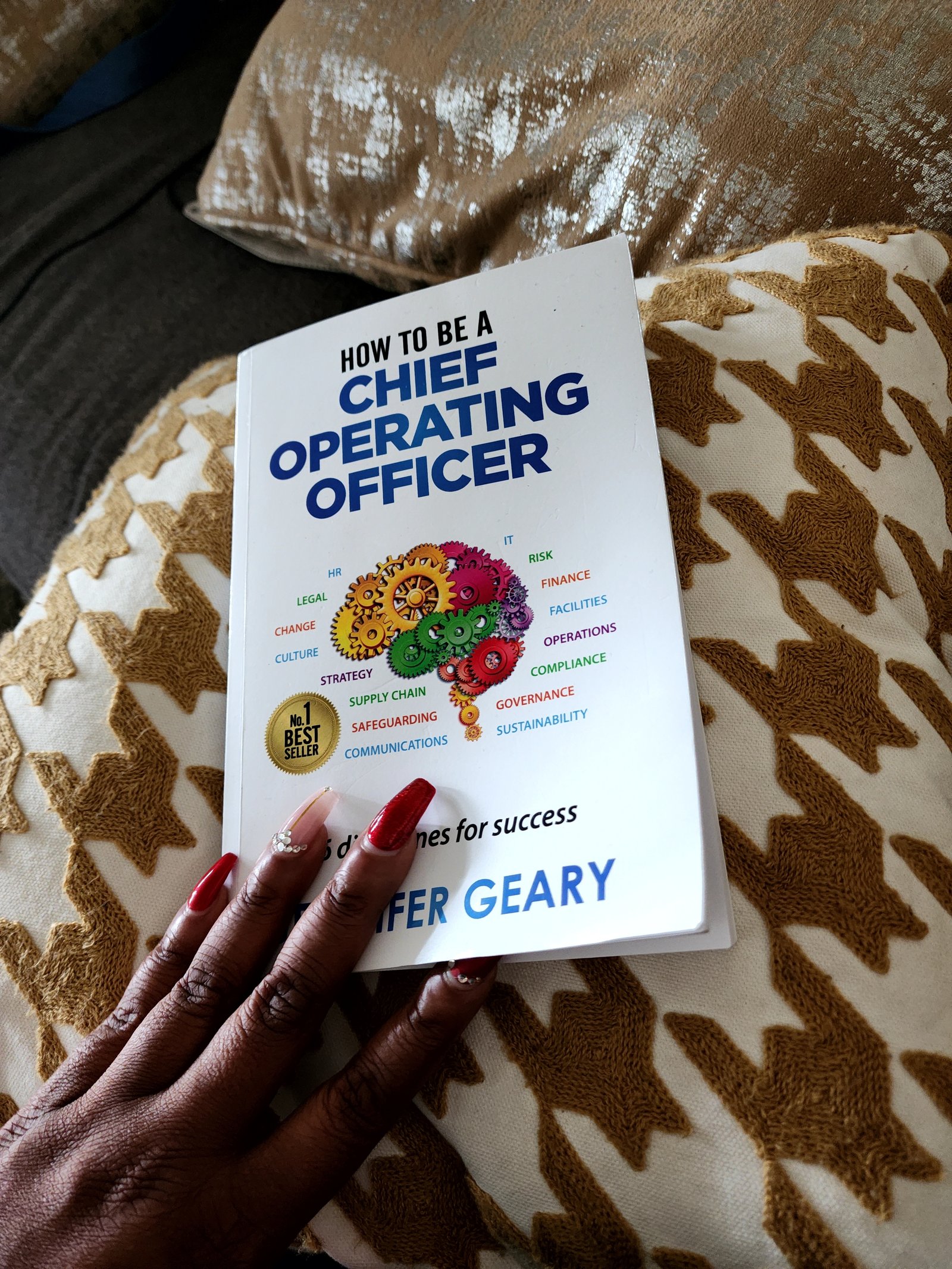 A hand holding the book How to Be a Chief Operating Officer