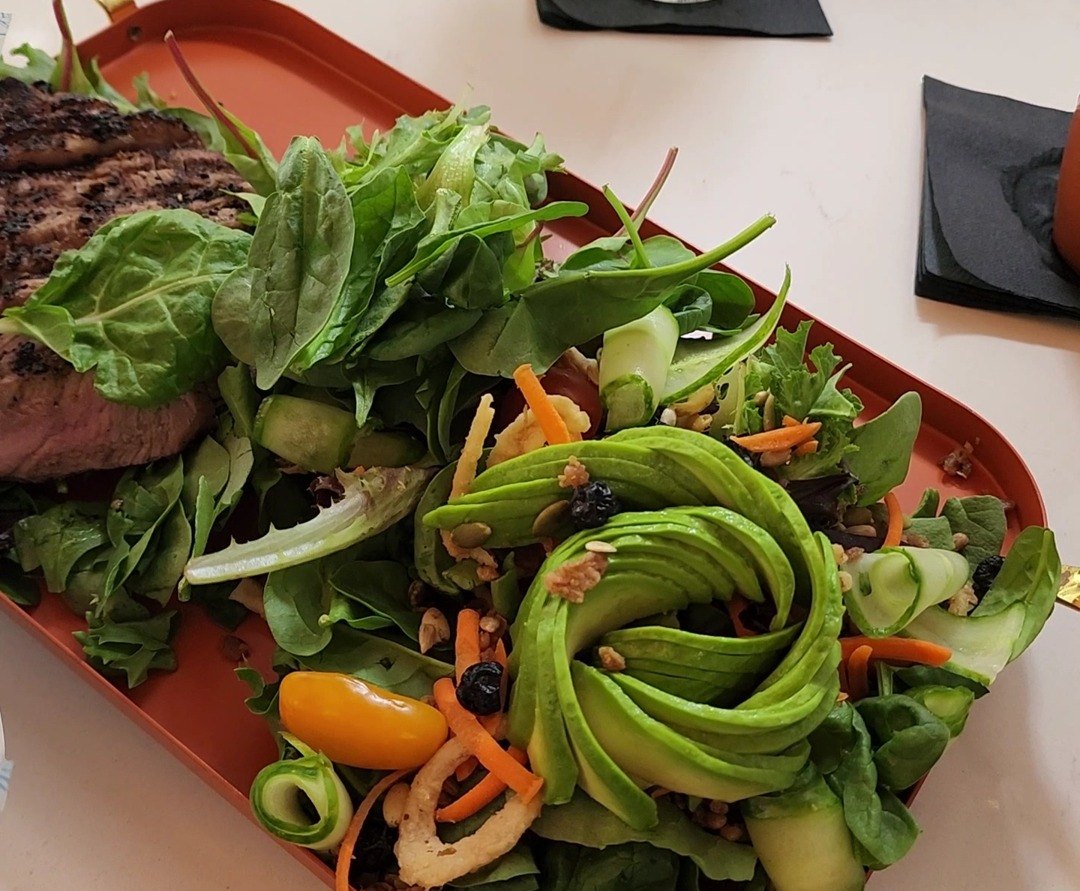 The house salad unwrapped, with an avocado rose and sliced steak