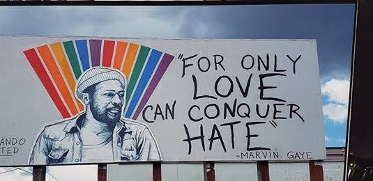 A mural of Marvin Gaye beside rainbow stripes and the words For only love can conquer hate