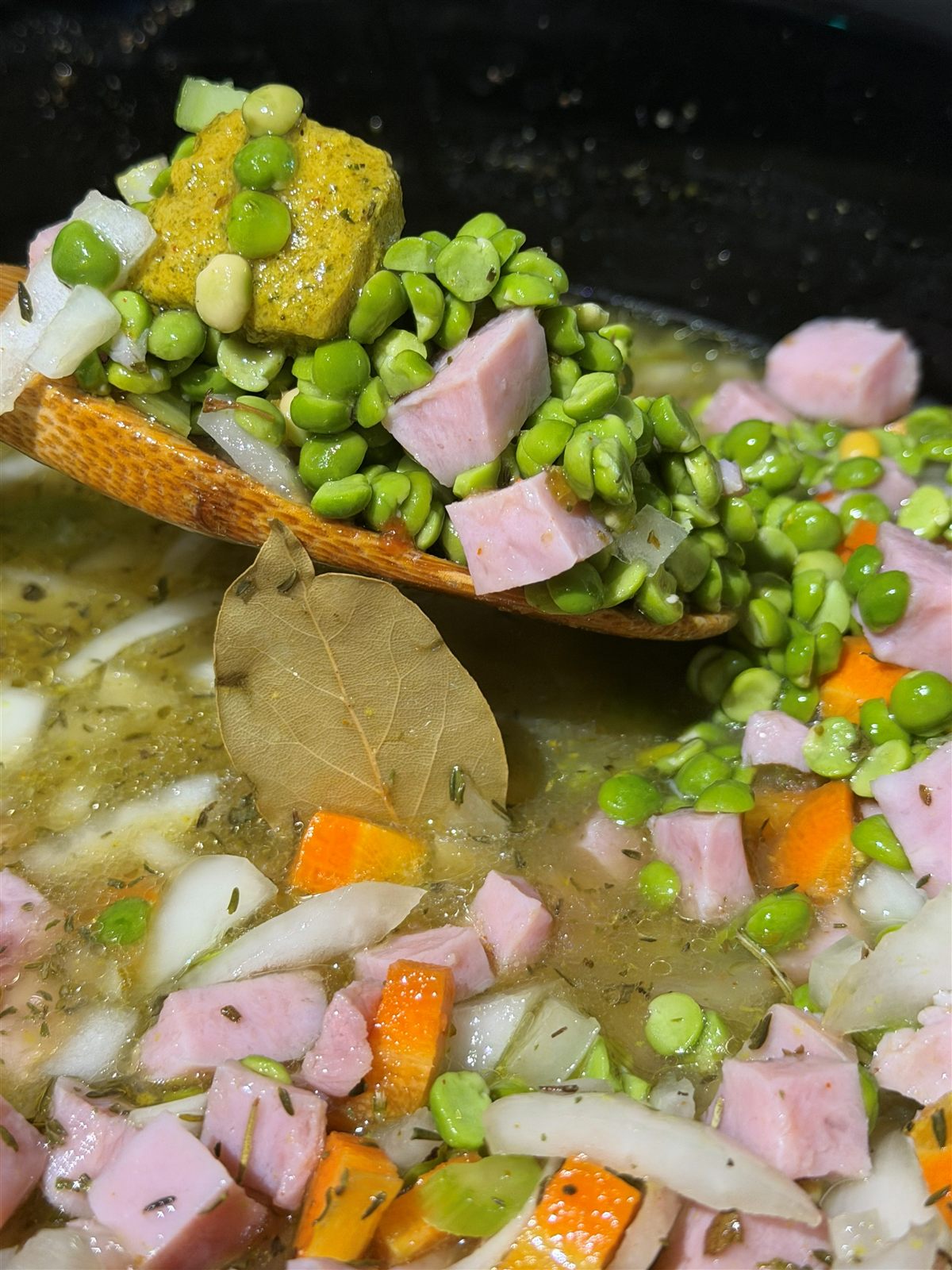 Split peas, diced ham, carrot, onion, celery, a bay leaf and bouillon paste in the slow cooker before cooking